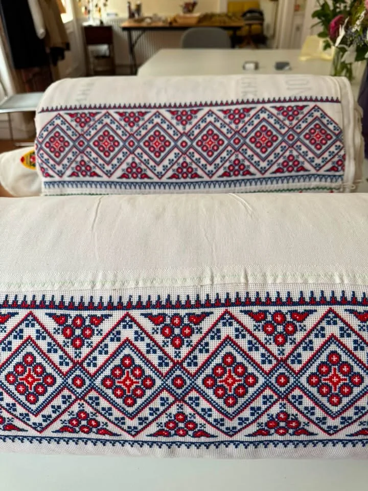 Red and blue geometric cross-stitch on two folded rushnyky.