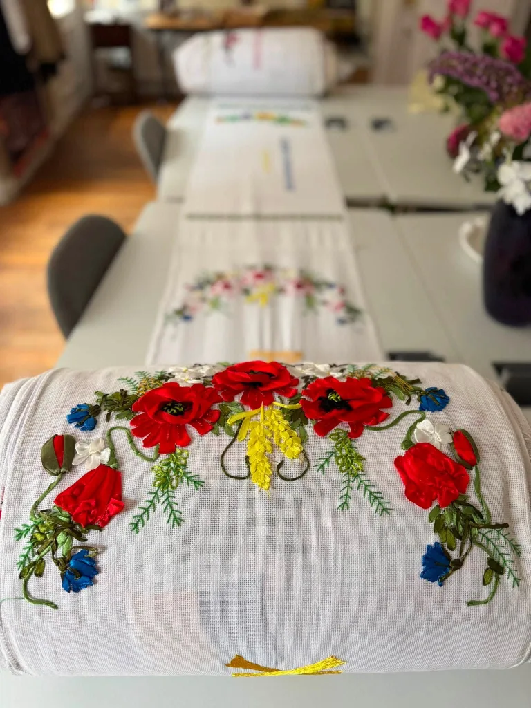 Ribbon-embroidered poppies and cornflowers on a white table runner.