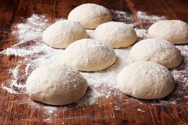 The same rounds of risen dough on a floured board, from further back.