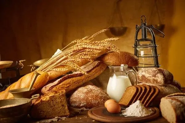 An assortment of breads and rolls with a sheaf of wheat, milk and eggs.
