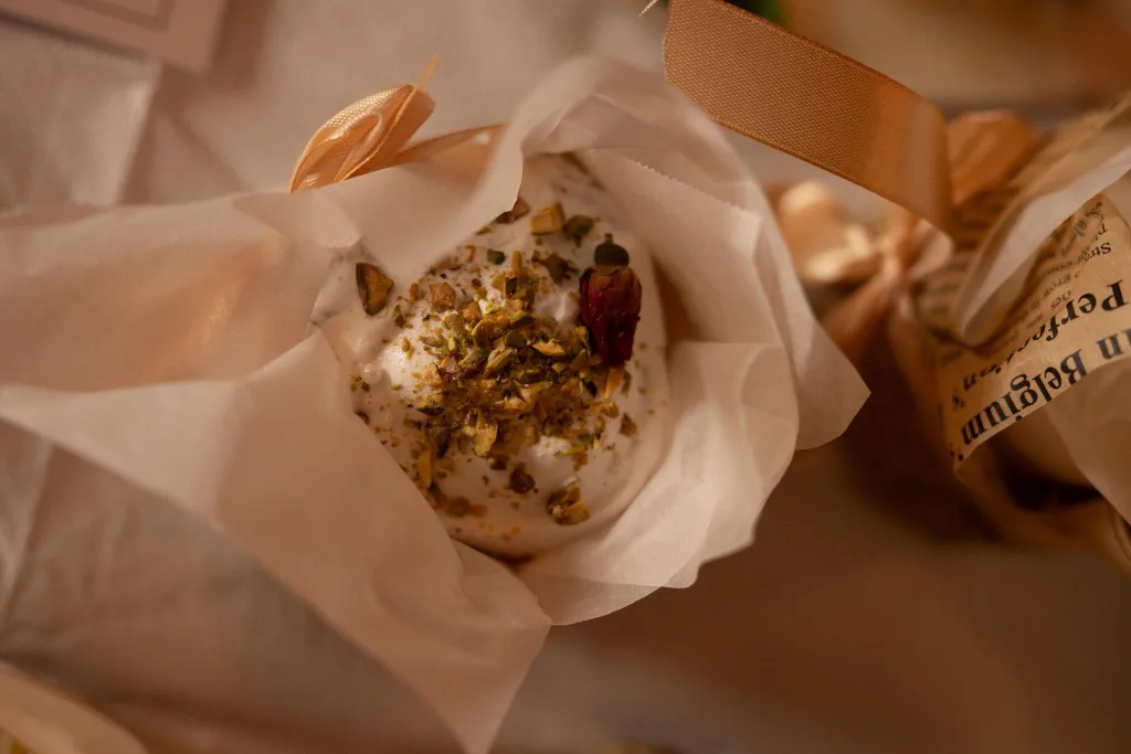 A decorated bun wrapped in paper, held in a bag.