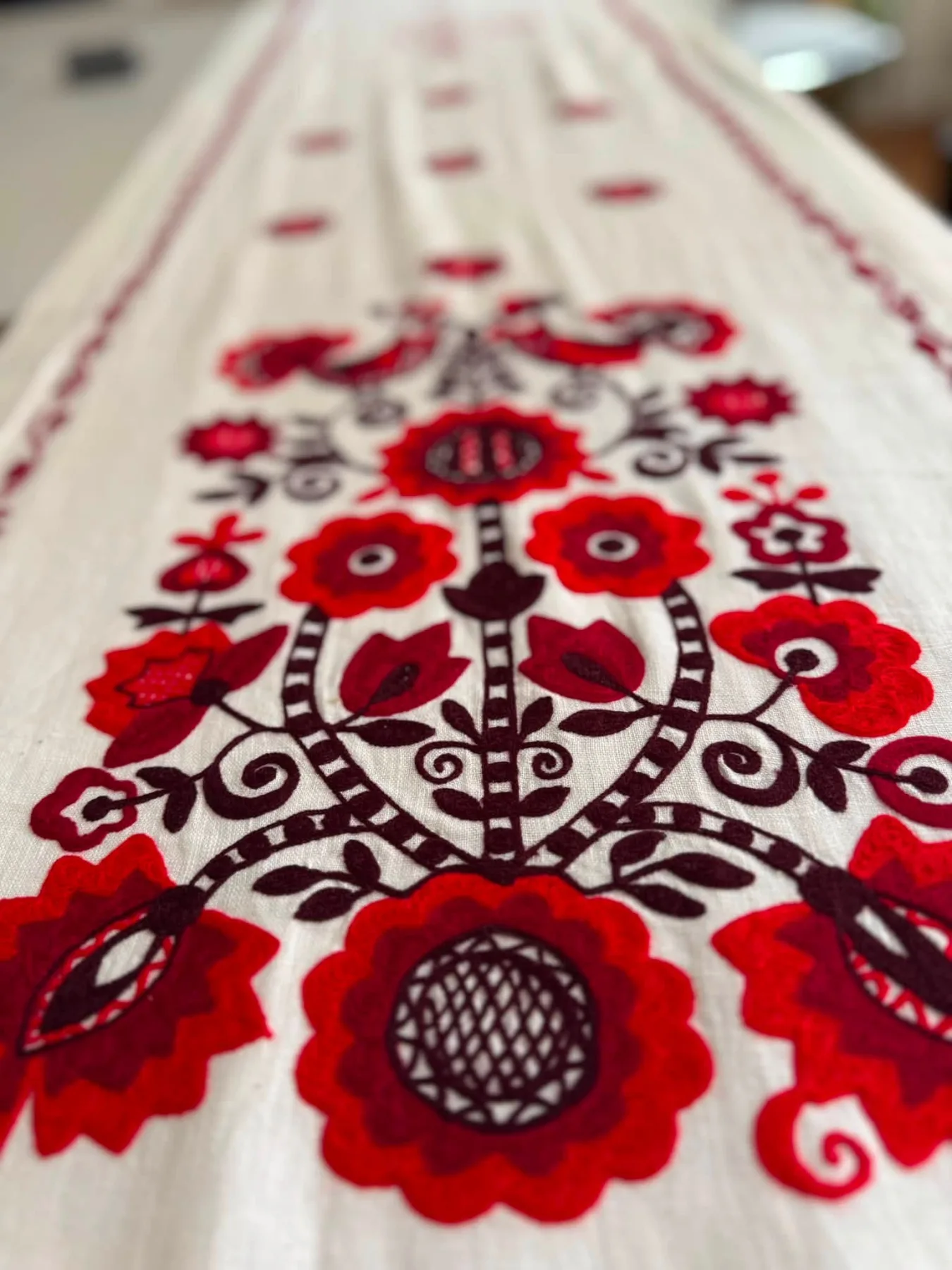 Red poppy embroidery running down a length of white linen