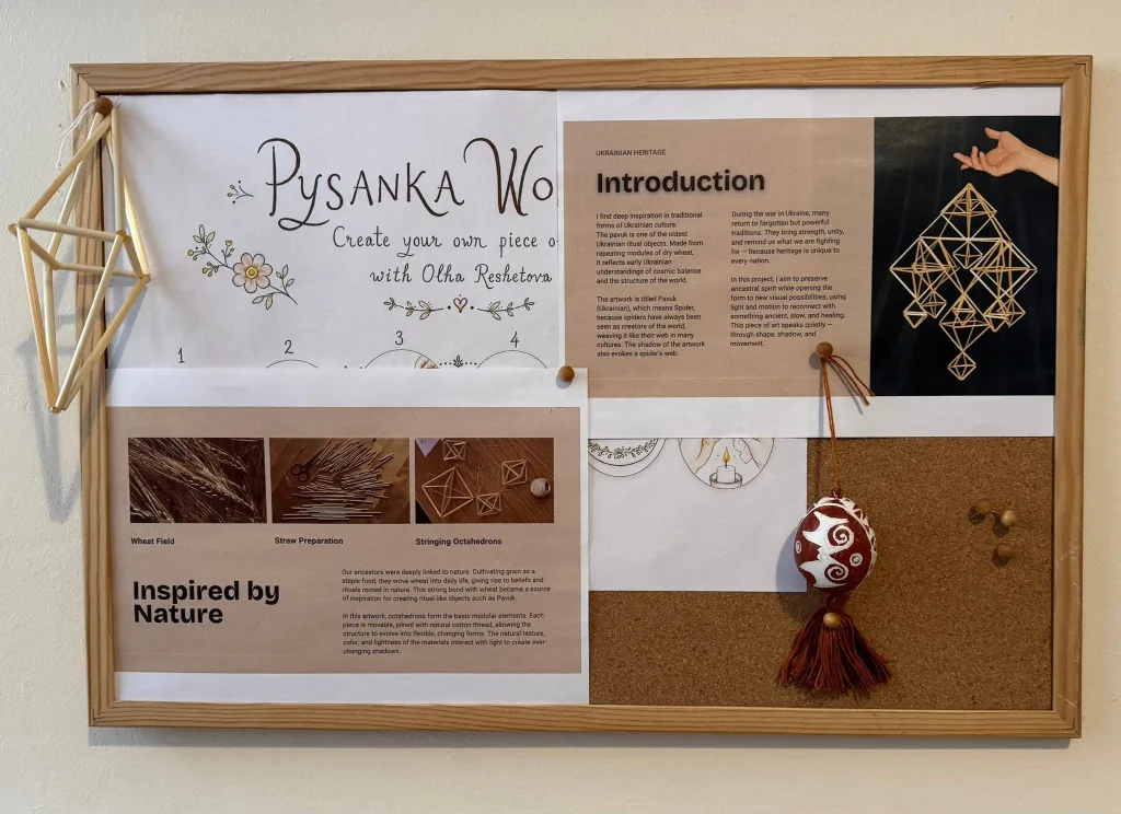 A display board with a pysanka workshop poster and a decorated egg hanging beside it.