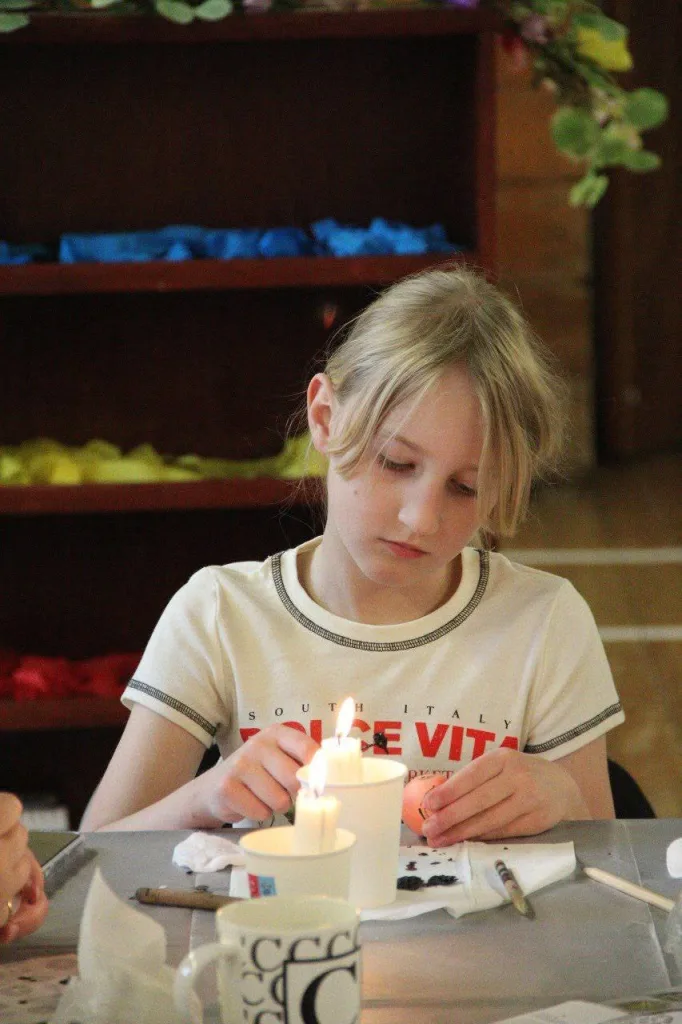 A child works on an egg over a candle flame.