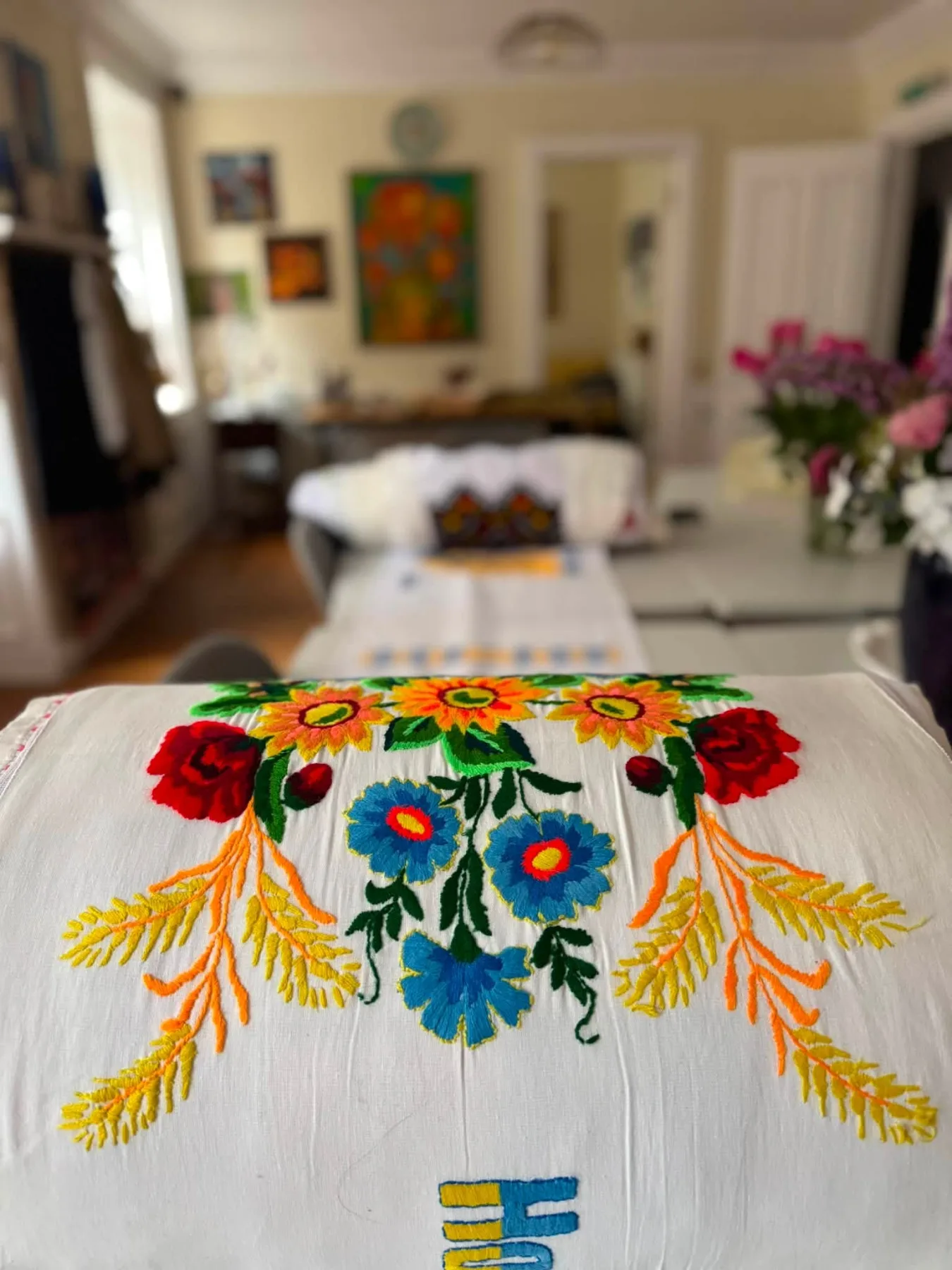 Embroidered cloths and vases of flowers laid out in the library room at Dutch Gable House